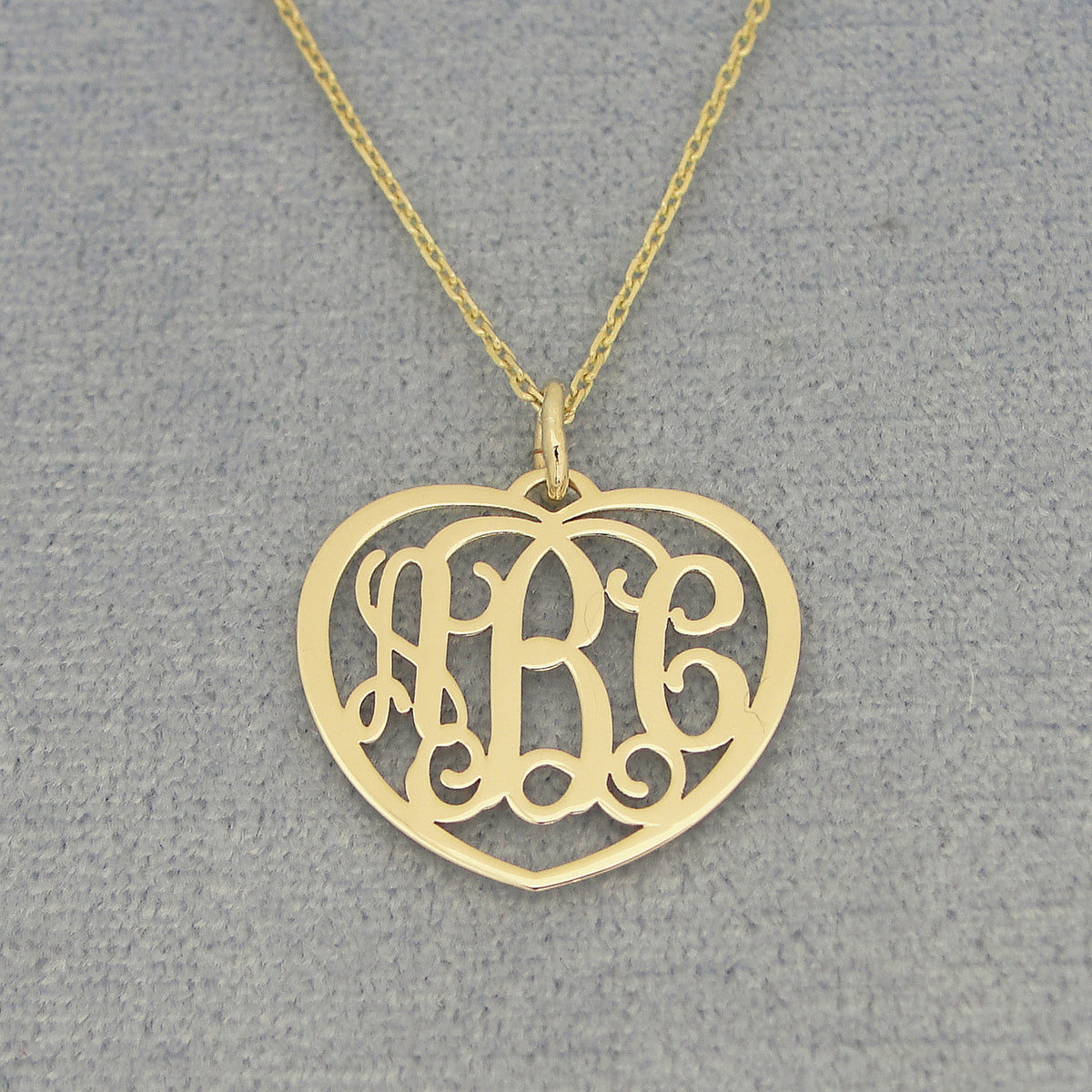 Small 10k or 14k solid gold heart monogram pendant with three custom initials on a gold chain.