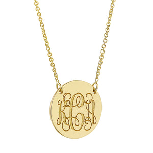 Close-up of a 1/2 inch solid gold monogram disc pendant featuring a Rolo chain.
