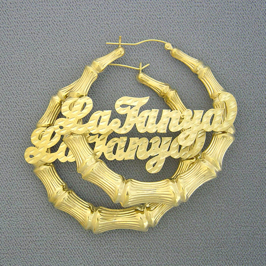 Pair of 10K / 14K solid gold personalized bamboo hoop earrings with custom diamond-cut cursive nameplates.