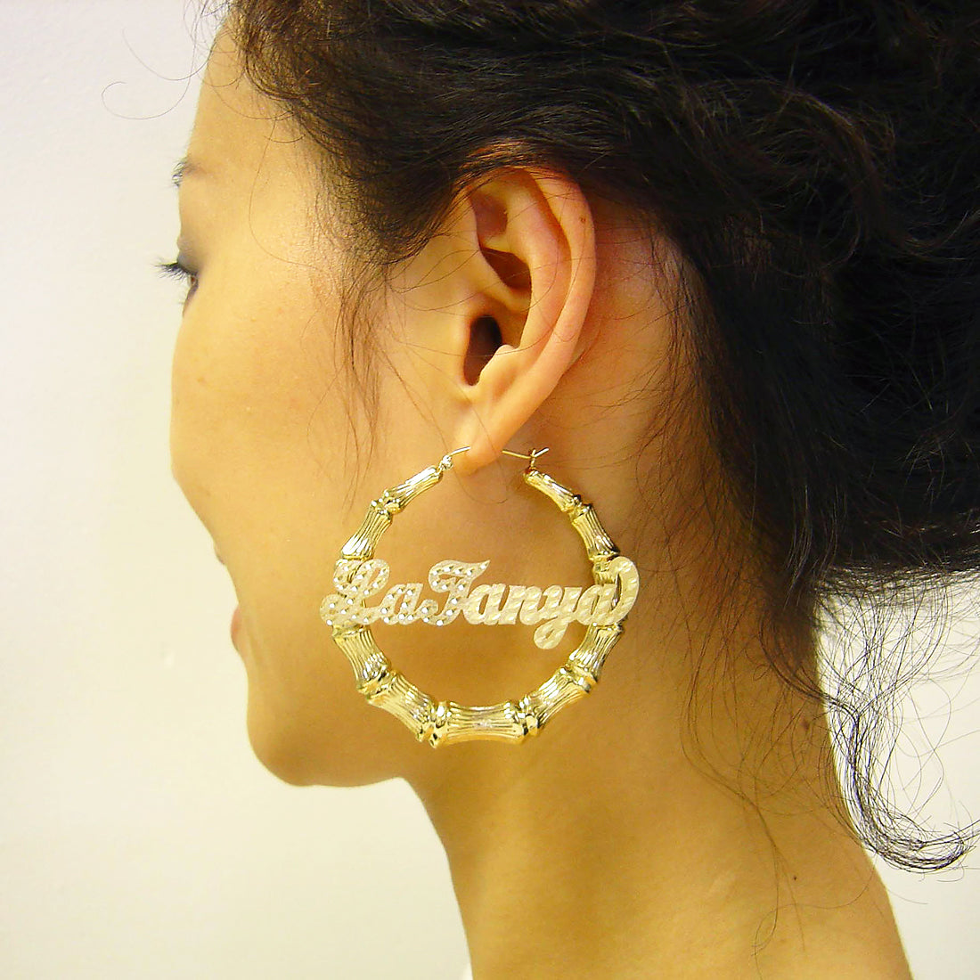 Model wearing 55mm (2 1/8 inch) 10K / 14K real gold custom name bamboo hoop earrings.