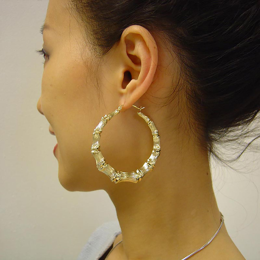 Woman wearing oversized 2.2 inch solid gold puffed bamboo doorknocker hoop earrings