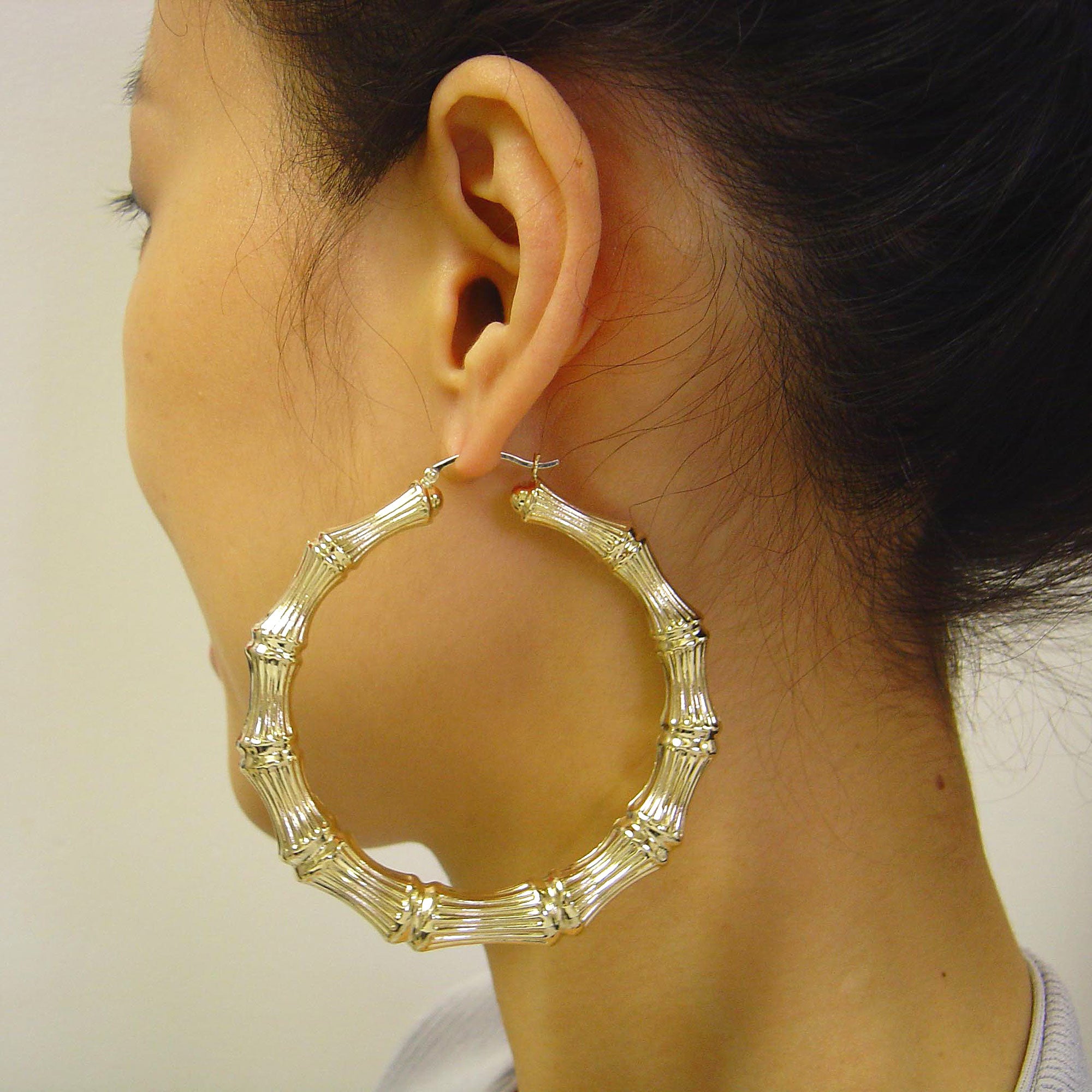 Woman wearing 2 7/8 inch large solid gold bamboo door knocker earrings