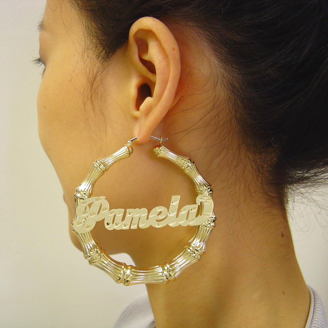 Model wearing 2.9-inch large custom gold bamboo name hoop earrings