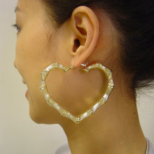 Model wearing 2.9 inch 10k solid gold skinny heart bamboo door knocker hoop earrings