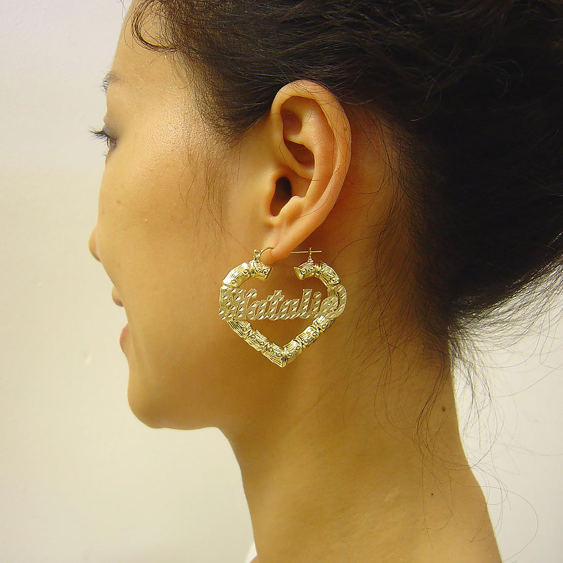 Model wearing 1.6-inch 10k gold personalized heart bamboo nameplate hoop earrings