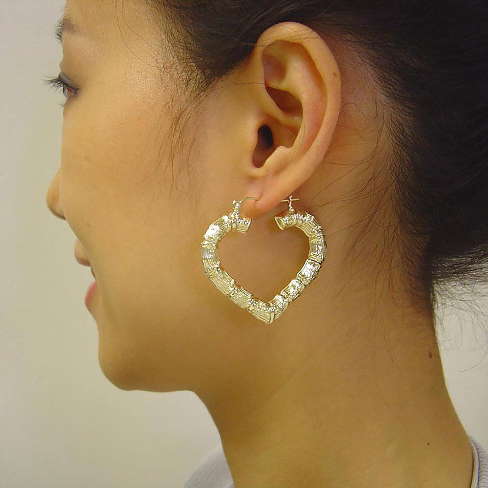 Model wearing 1 5/8 inch 10K yellow gold skinny heart bamboo hoop earrings.
