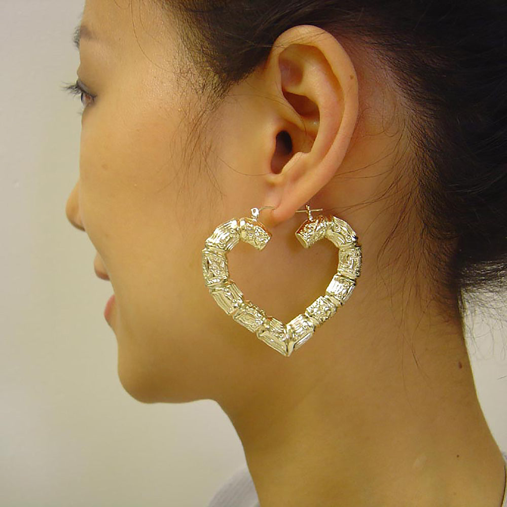 Model wearing large 2.1 inch 10K yellow gold heart-shaped bamboo hoop earrings