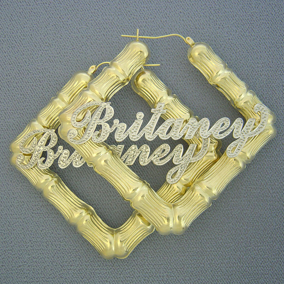 Detail view of custom 2-tone iced out cursive nameplate on 10k gold square bamboo earring