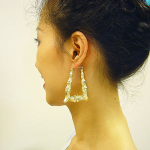 Model wearing 1.75 inch 10K solid gold rectangular bamboo doorknocker hoop earrings