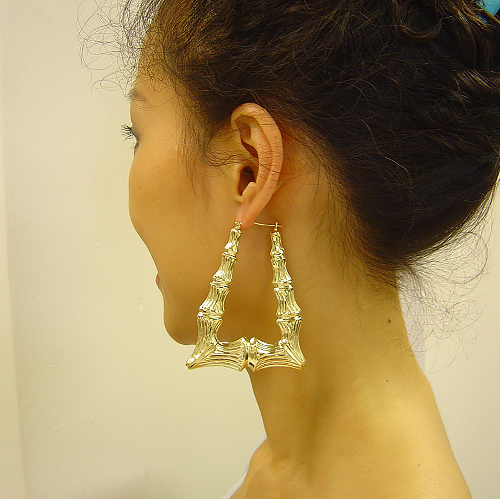 Woman wearing extra large 2.3 inch 10K yellow gold rectangular bamboo door knocker hoop earrings