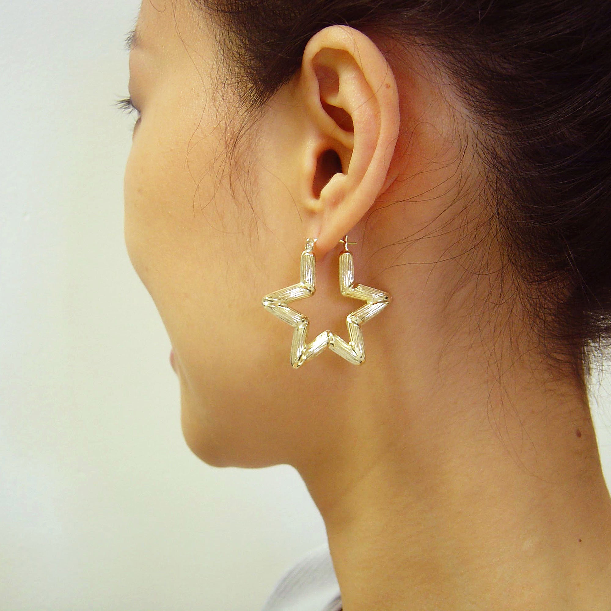 Model wearing 10K yellow gold star bamboo doorknocker hoop earring