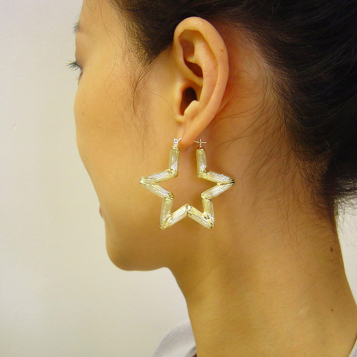 10K yellow gold puffed star bamboo hoop earrings on model.