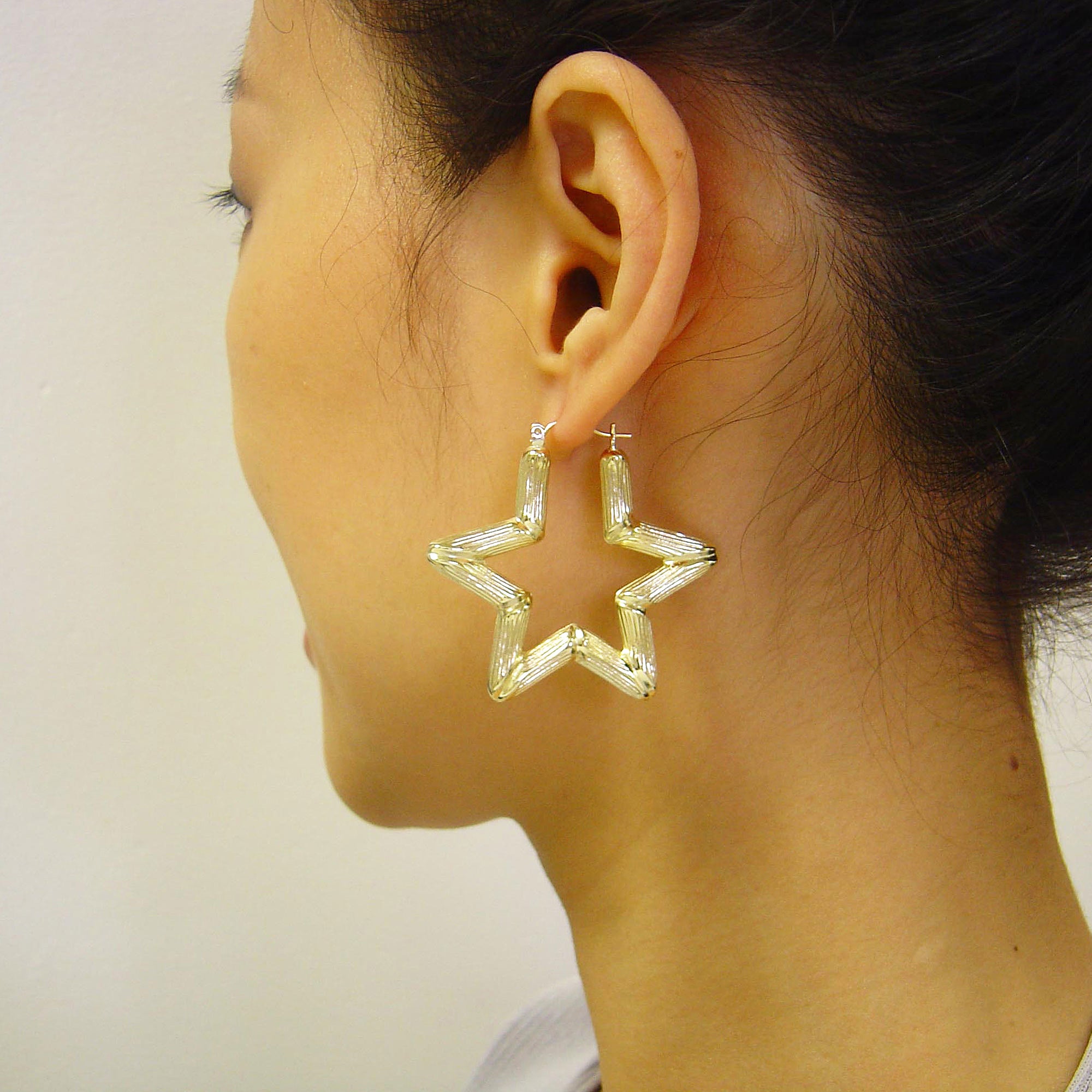 10K yellow gold puffed star bamboo hoop earrings on model.