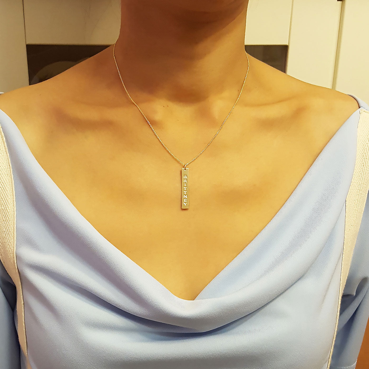 Dainty personalized solid 14k gold vertical bar nameplate necklace worn on model