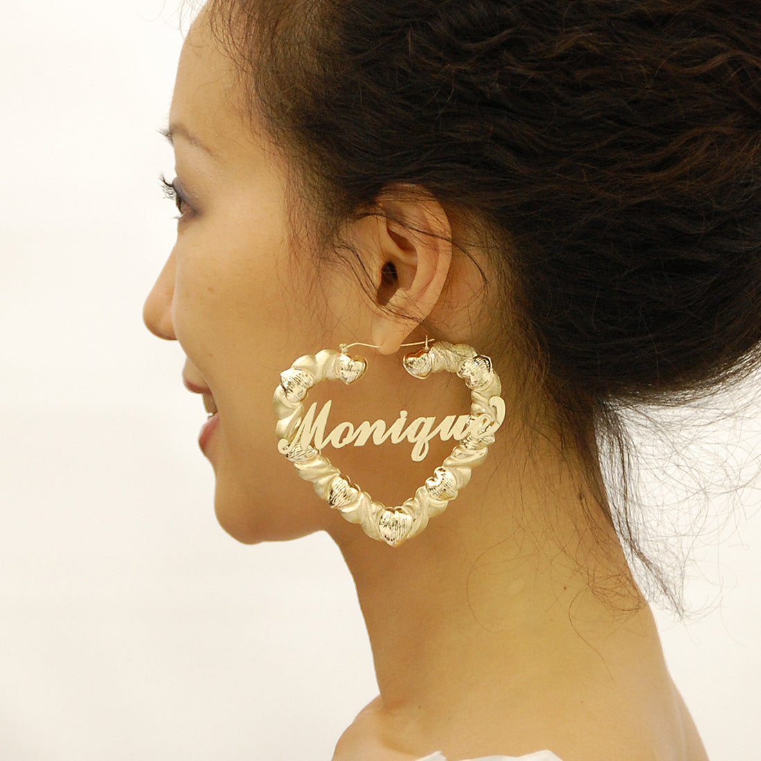 Close up of personalized cursive name script on 10k gold diamond cut heart earrings