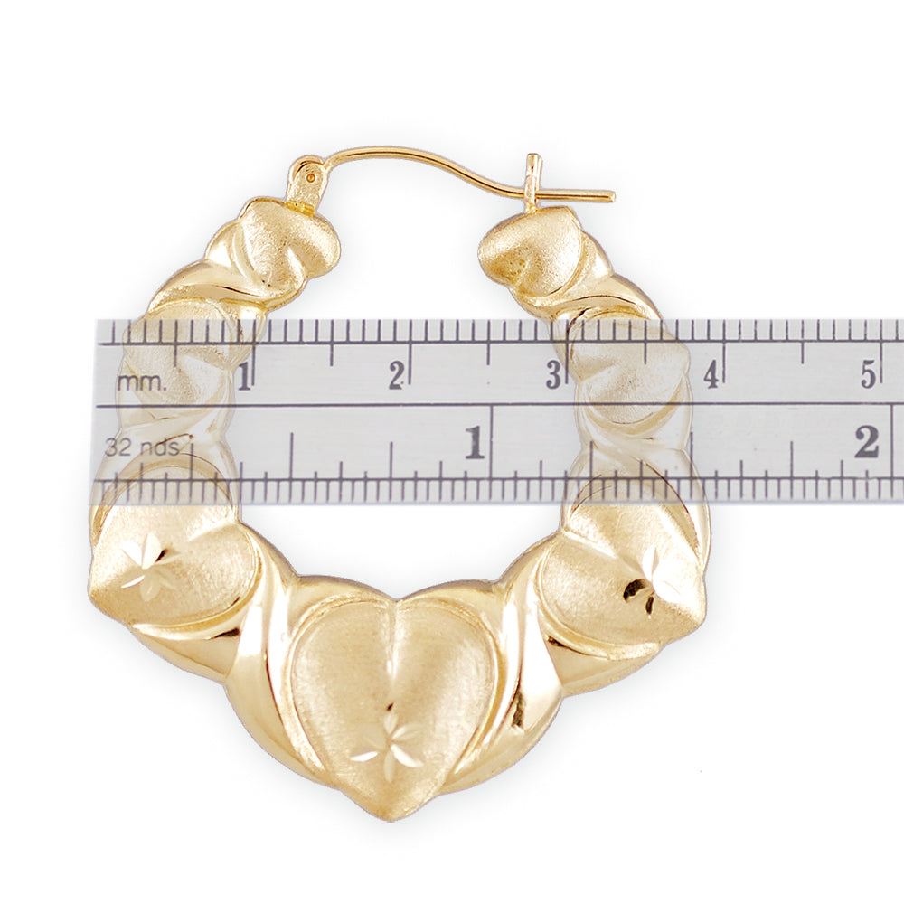 Close-up of diamond-cut details on 10K yellow gold puffed XO heart door knocker earrings