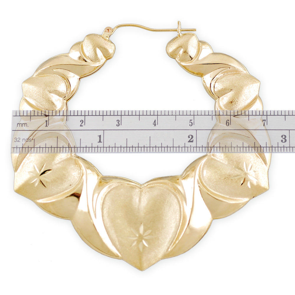 Close-up of 10K yellow gold puffy XO heart doorknocker earring showing diamond-cut finish