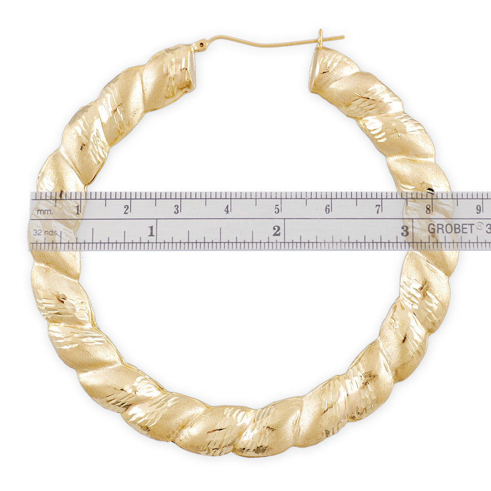 Close-up of diamond-cut texture and hinged snap-bar closure on 10K gold twisted door knocker earring