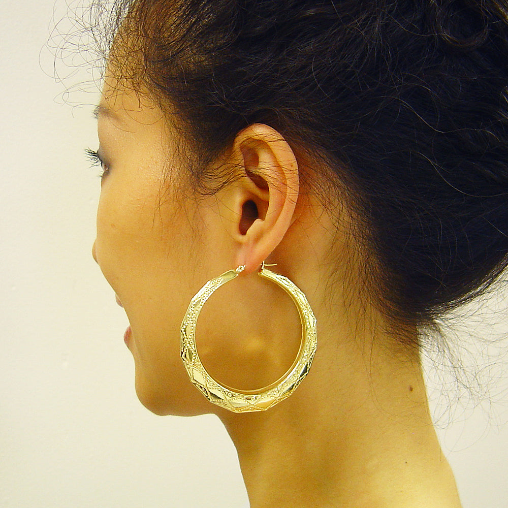 Woman wearing 10k yellow gold 2.25 inch puffy door knocker hoop earrings