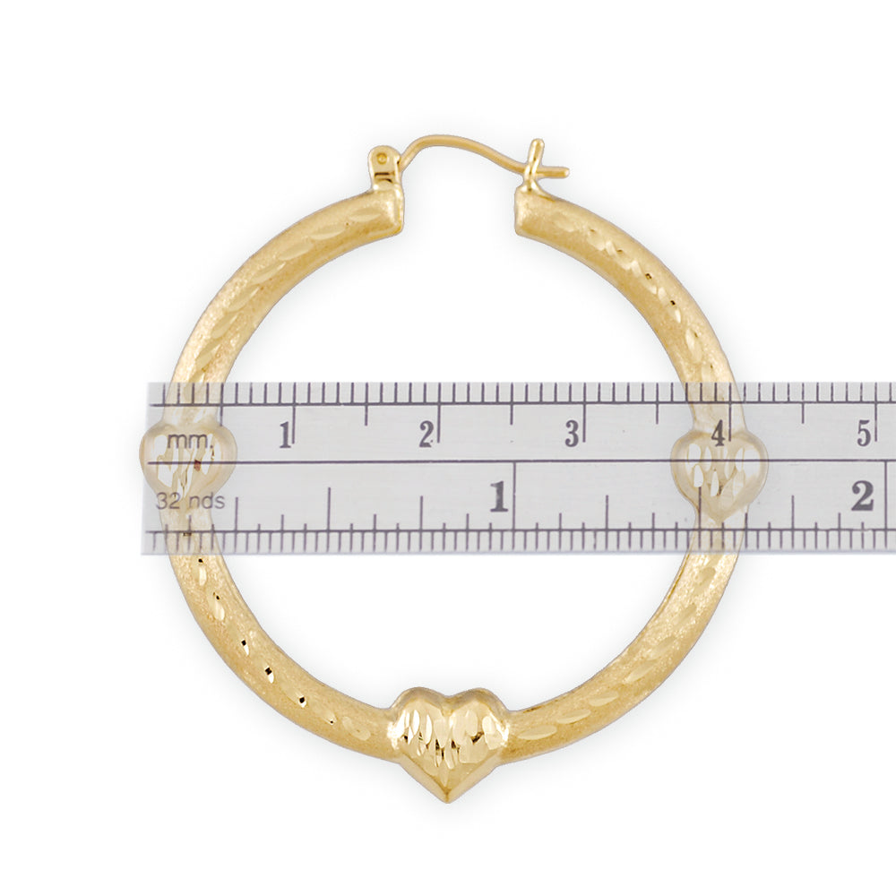 Detailed view of 10K gold diamond-cut layered puffy heart doorknocker earrings