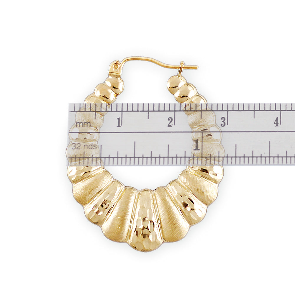 Close-up of diamond-cut texture on 10K gold hollow puffy doorknocker hoop earrings