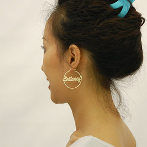 Model wearing custom 14k yellow gold name hoop earrings 40mm diameter