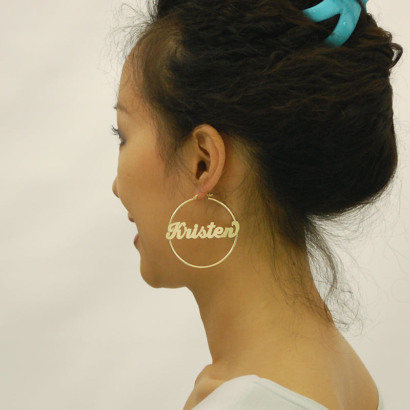 Close-up of custom nameplate on 14K yellow gold hoop earring showing shiny cursive font detail