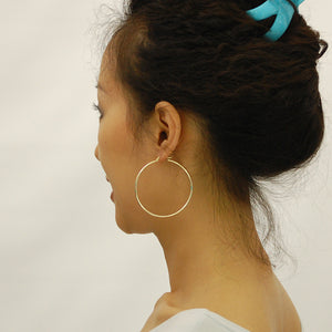 Woman wearing 2.1 inch 14K yellow gold 2mm hollow hoop earrings