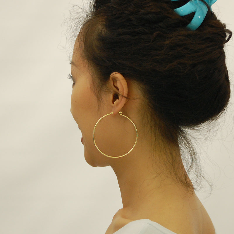Model wearing 2.3 inch 14k yellow gold 2mm thick hollow hoop earrings