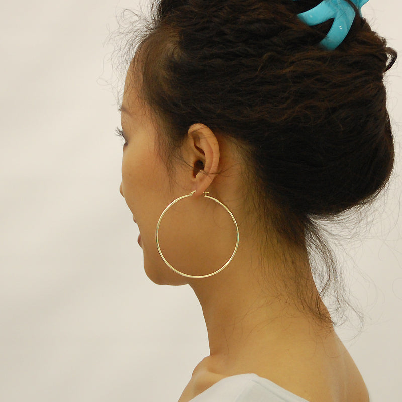 Model wearing 14k yellow gold 2.5 inch large hollow hoop earrings