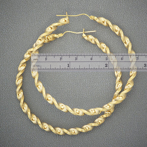 Close-up view of 4mm hollow twisted gold hoop earrings showing detailed texture and shine
