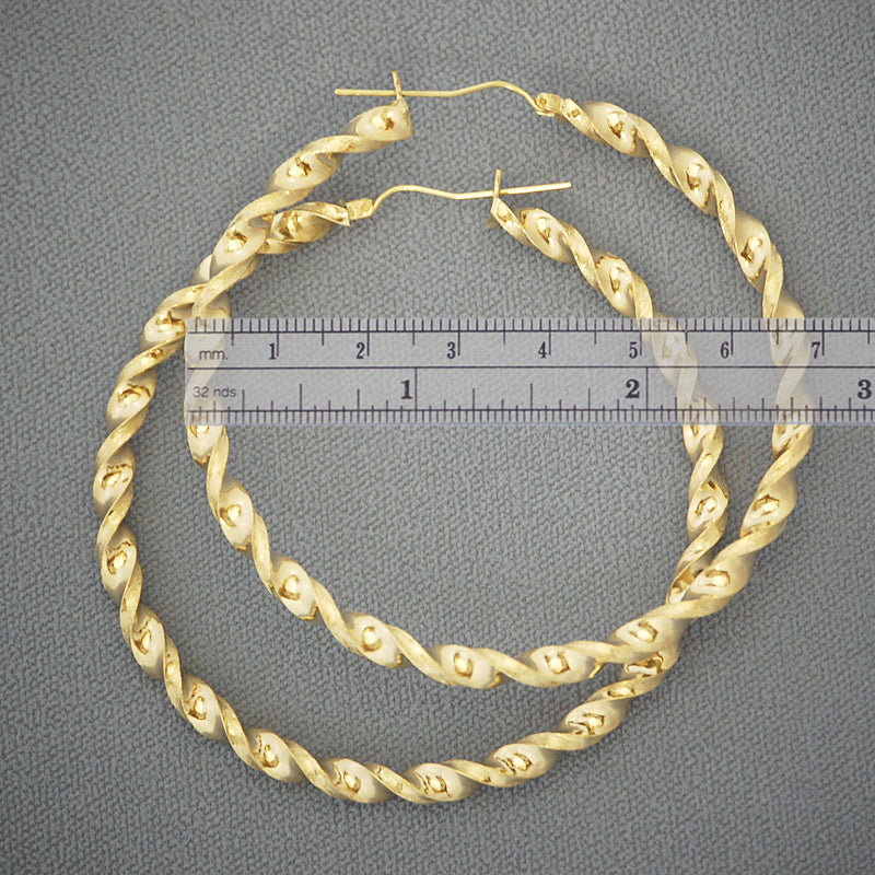 Close-up view of 4mm hollow twisted gold hoop earrings showing detailed texture and shine