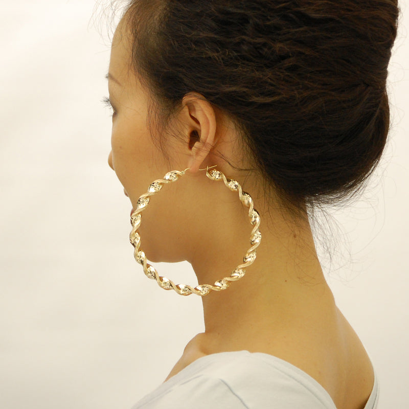 Model wearing extra large 3.5 inch 10K yellow gold 8mm twisted hoop earrings