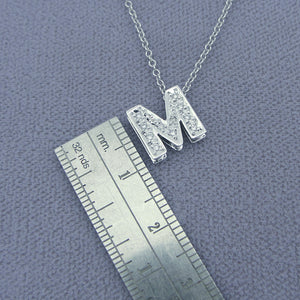 Close-up detail of genuine pave diamonds set in solid gold letter M pendant