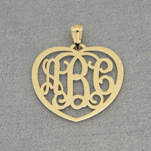Flat lay of personalized solid gold heart monogram pendant with three initials on gray background
