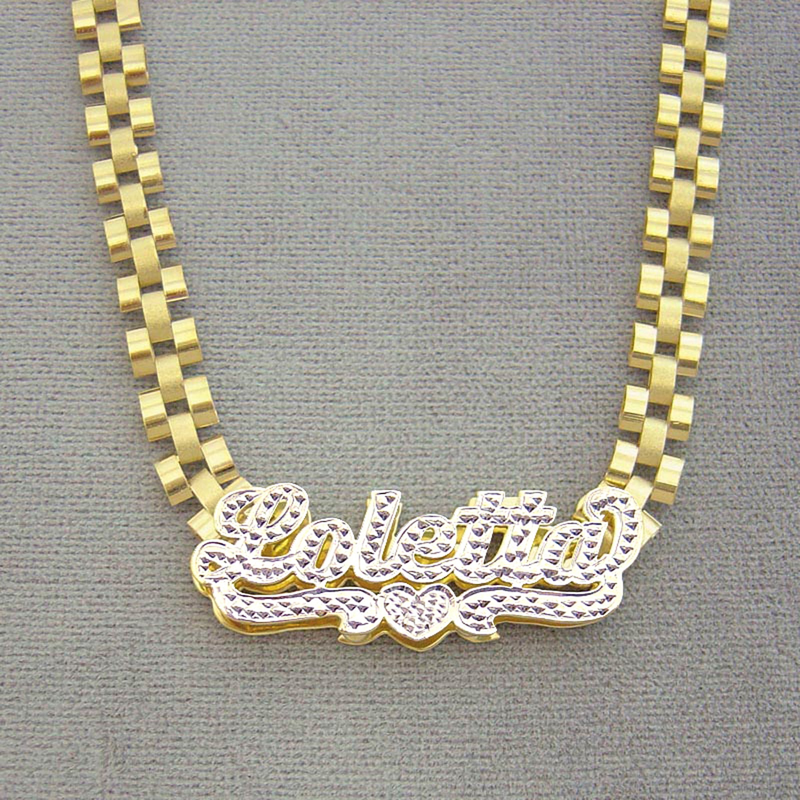 Custom 10K yellow gold iced out nameplate laying flat on 6mm watch-band style chain
