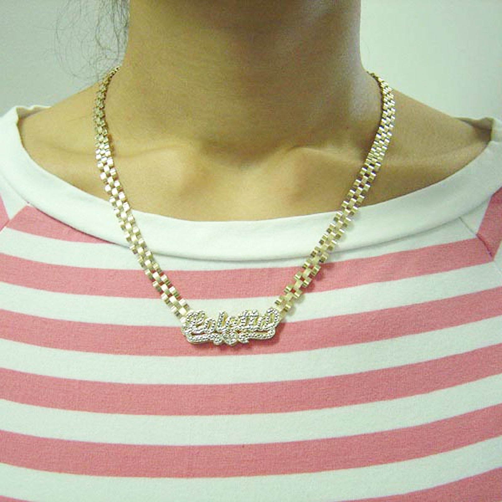 Model wearing custom 10K gold iced out nameplate necklace on striped shirt