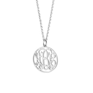 Close-up of laser-cut sterling silver circle monogram pendant showing intricate initial detail