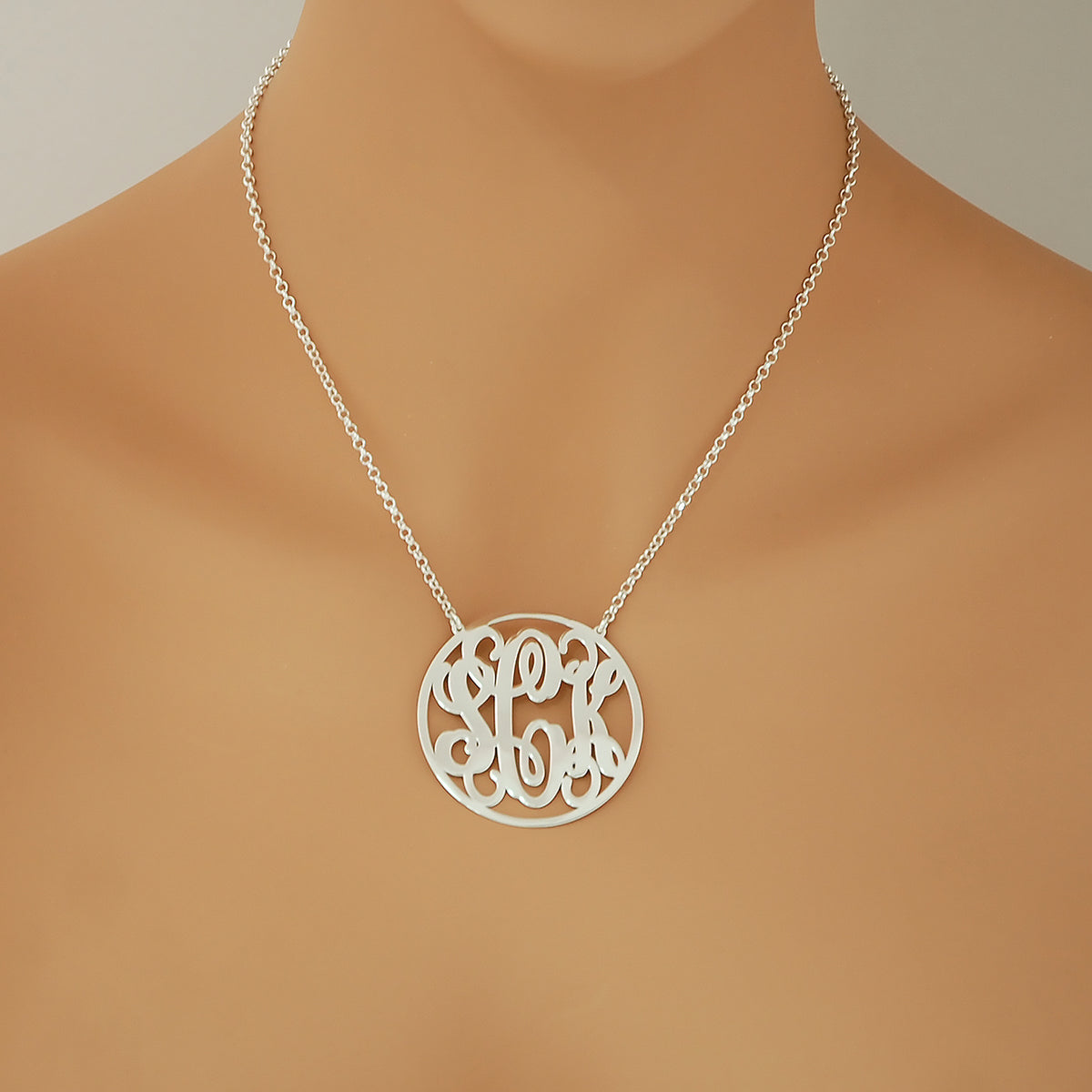 Woman wearing a personalized sterling silver 3-initial circle monogram necklace attached to a silver rolo chain.