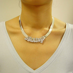 Model wearing a personalized sterling silver 3D nameplate pendant on a thick herringbone chain.