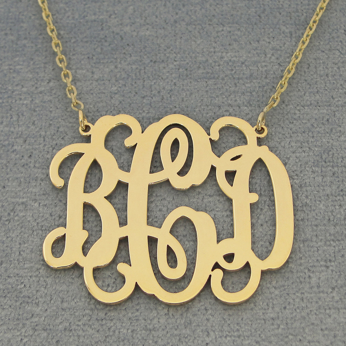 Custom solid gold 3 initial monogram necklace on a dark background