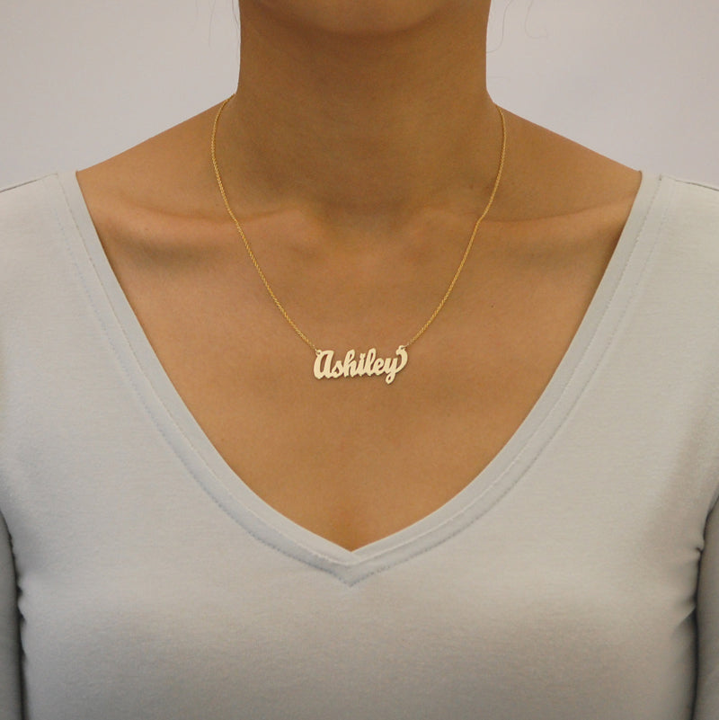Model wearing a custom gold cursive script nameplate necklace handcrafted in solid gold.