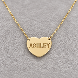 Close-up of a solid gold heart necklace with ASHLEY laser engraving