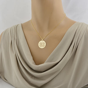 Layered solid gold monogram disc pendant necklace shown on a display mannequin