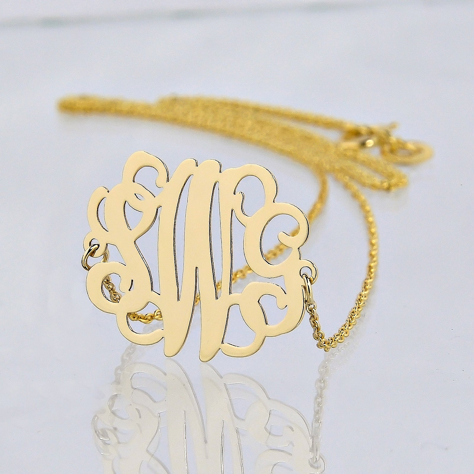 Close-up of a laser-cut 14K solid gold three-initial monogram pendant necklace.
