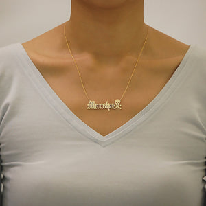 Model wearing custom solid gold Old English name necklace featuring a skull accent, handcrafted in Los Angeles.