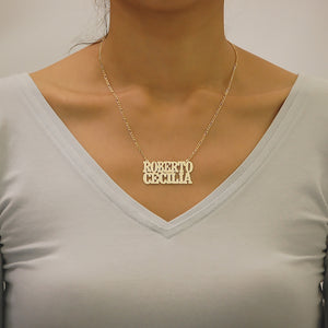 Model wearing a personalized solid gold two name nameplate necklace on an 18-inch Figaro chain.