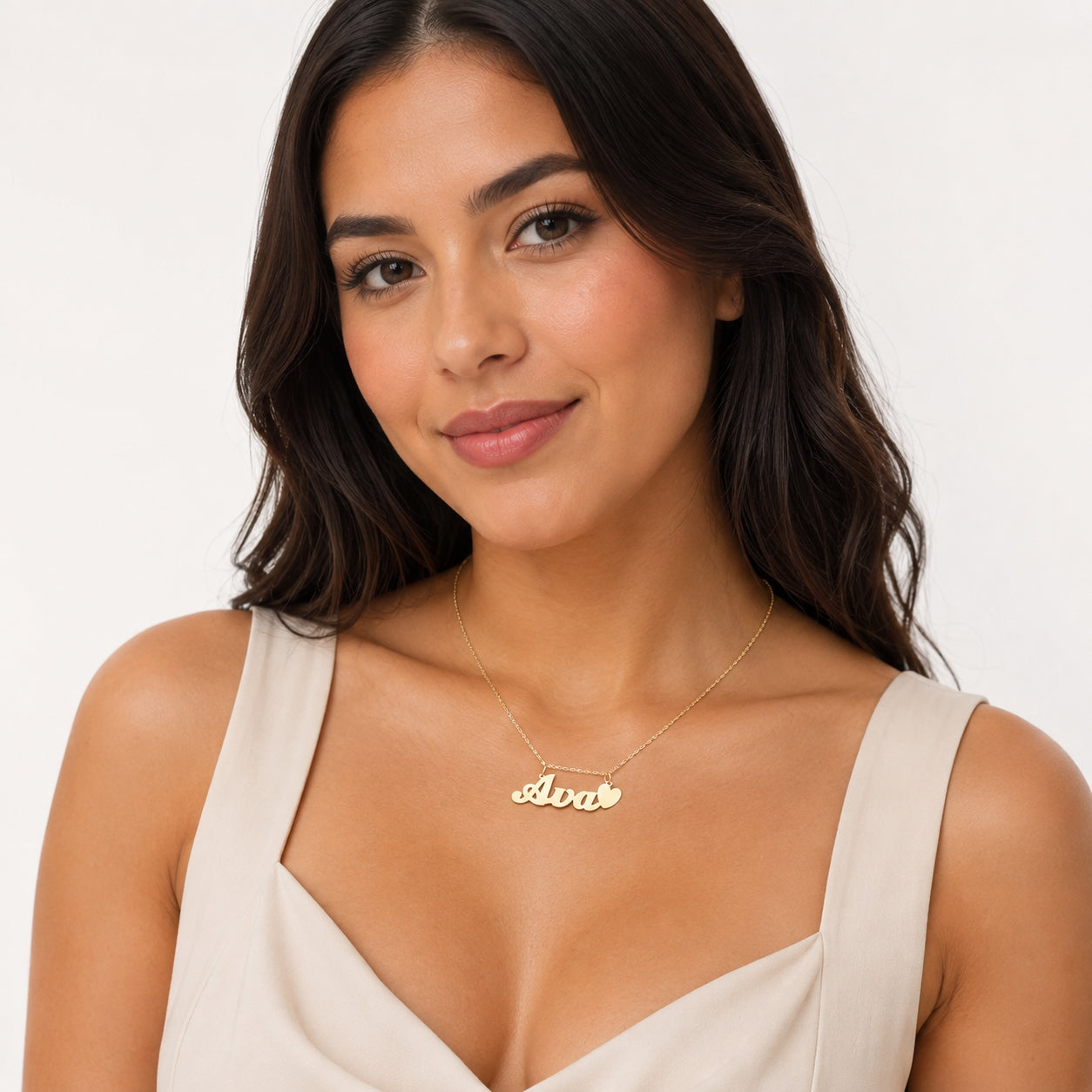 Woman wearing the custom small 10k gold Ava script nameplate pendant with a heart accent on a gold chain.