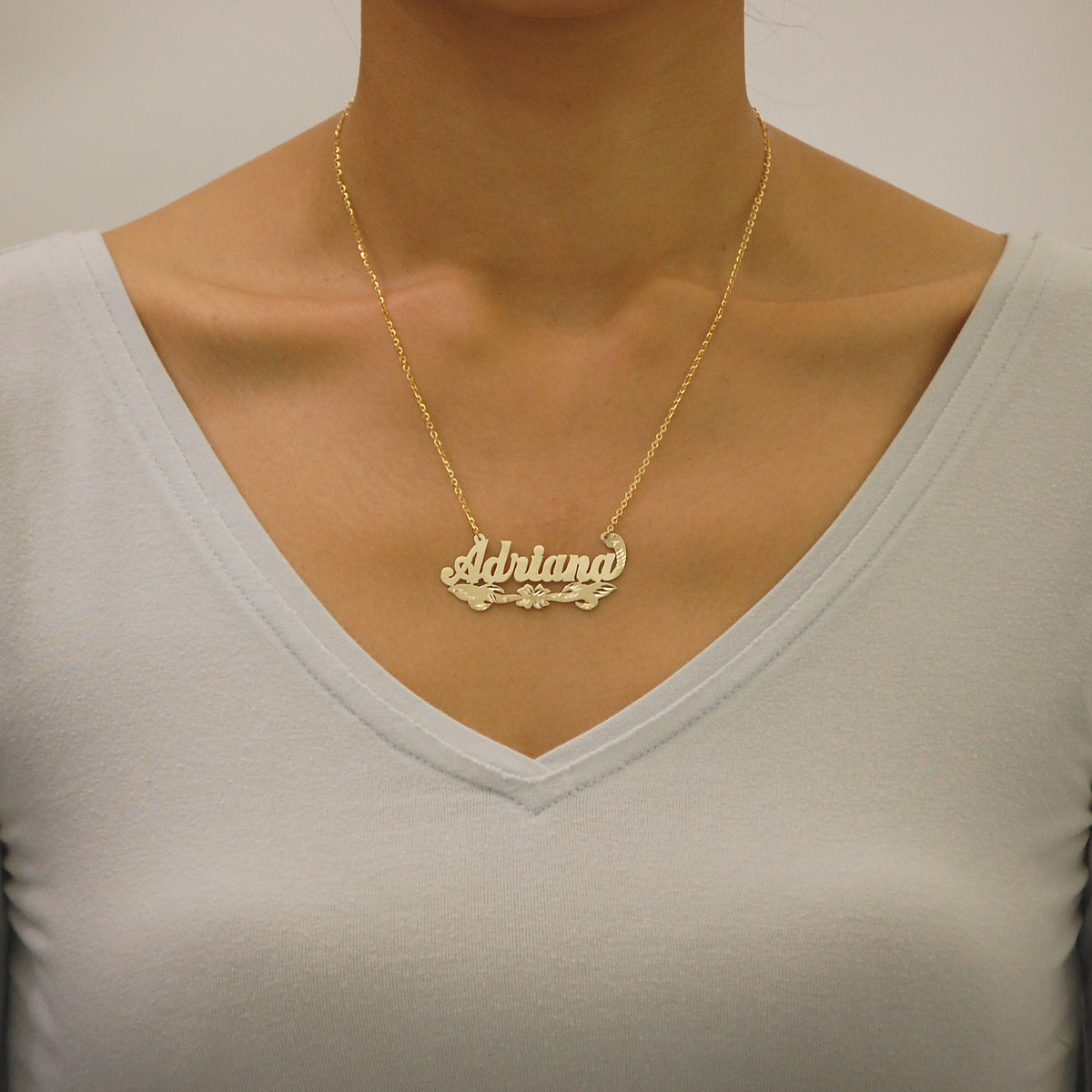 Close-up of a woman wearing the solid gold custom nameplate necklace on an 18-inch split chain.
