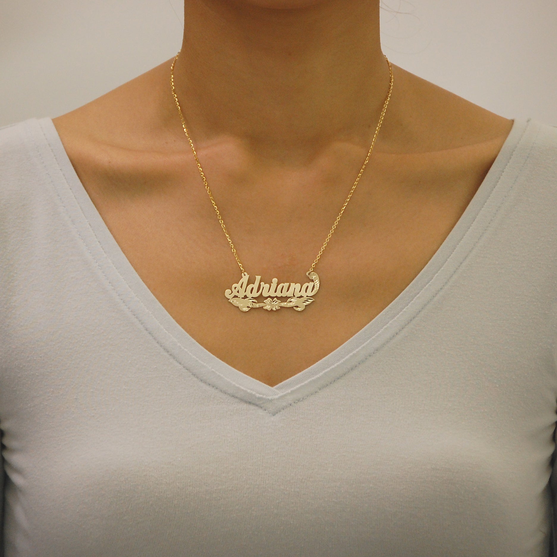 Close-up of a woman wearing the solid gold custom nameplate necklace on an 18-inch split chain.